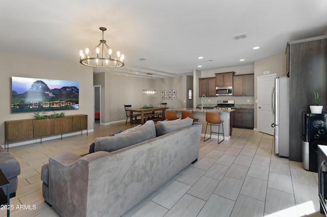 living room featuring light wood finished floors, recessed lighting, visible vents, a chandelier, and baseboards