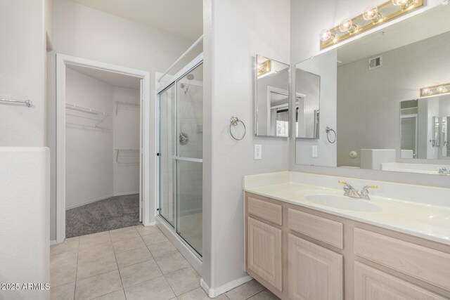 15380 N 100th St Unit 1106, Scottsdale, AZ 85260 - bathroom featuring a stall shower, vanity, a walk in closet, tile patterned floors, and baseboards