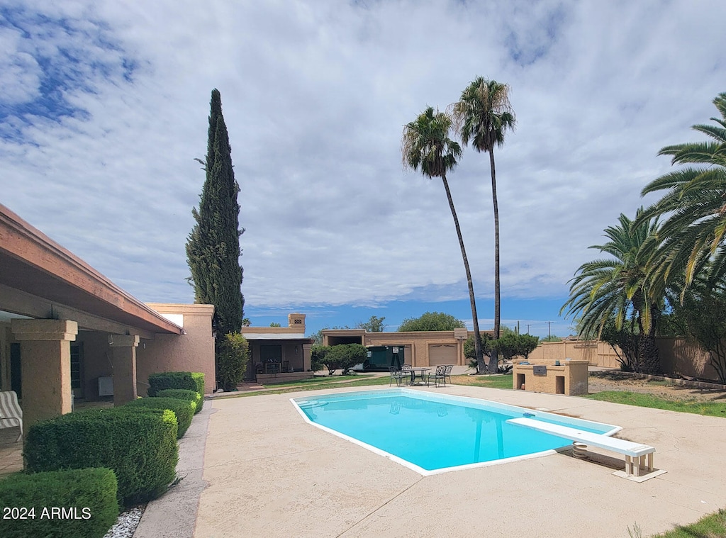 view of swimming pool with a diving board and a patio area