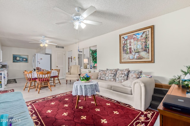 living room featuring a textured ceiling, hardwood / wood-style floors, and ceiling fan