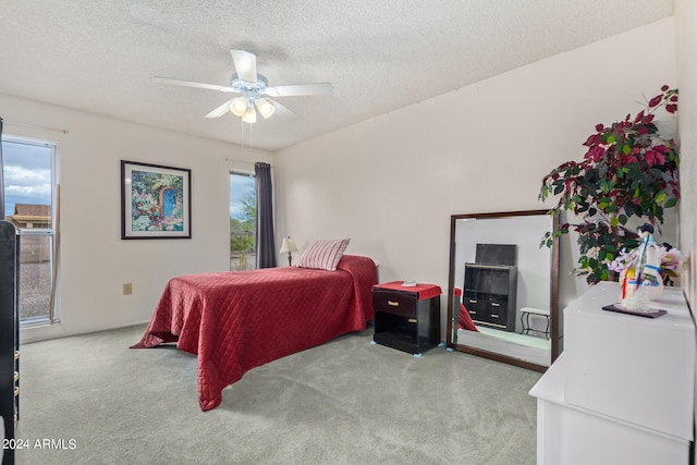 bedroom featuring multiple windows, a textured ceiling, ceiling fan, and light colored carpet