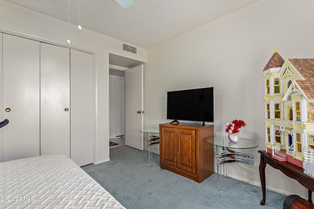 bedroom with a textured ceiling, light colored carpet, and a closet