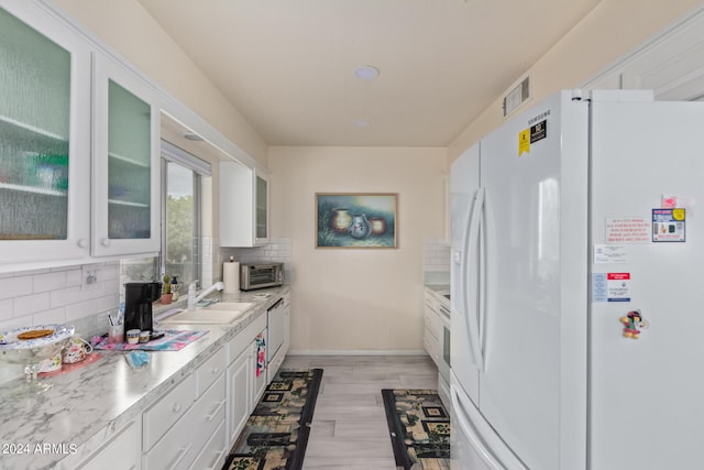 kitchen featuring decorative backsplash, white cabinets, white refrigerator, light wood-type flooring, and sink