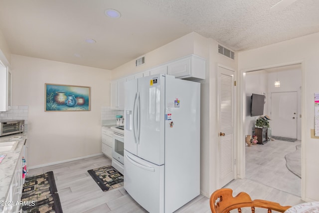 kitchen with light hardwood / wood-style floors, white appliances, white cabinetry, and tasteful backsplash