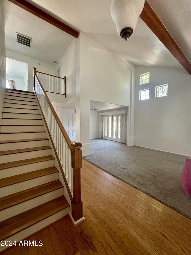 entrance foyer featuring hardwood / wood-style flooring, beam ceiling, high vaulted ceiling, and a textured ceiling