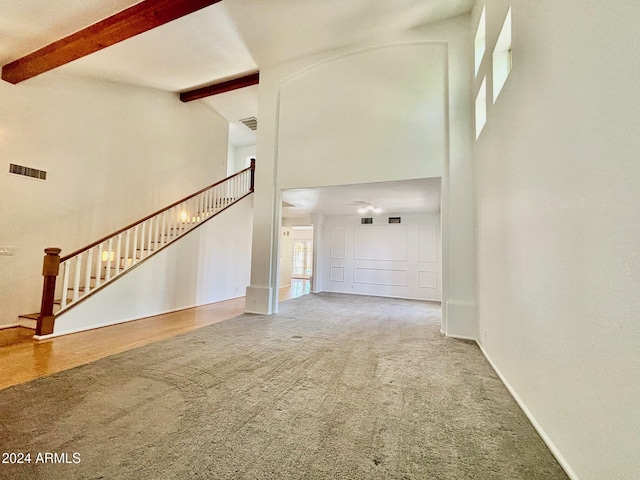 unfurnished living room featuring beamed ceiling, carpet flooring, and high vaulted ceiling