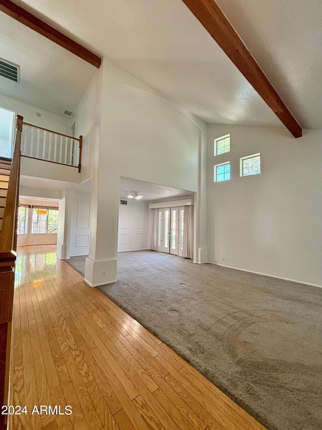 unfurnished living room with beamed ceiling, high vaulted ceiling, and hardwood / wood-style floors