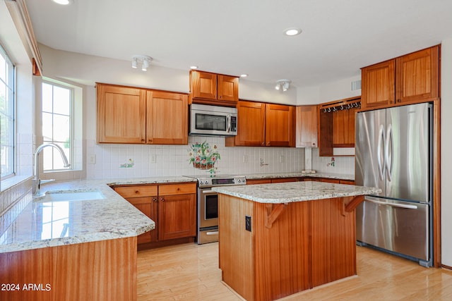 kitchen featuring stainless steel appliances, light wood-type flooring, sink, and a center island