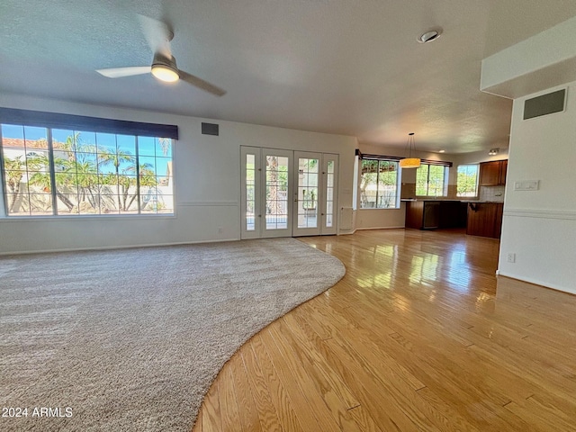 unfurnished living room with french doors, ceiling fan, a textured ceiling, and light hardwood / wood-style flooring