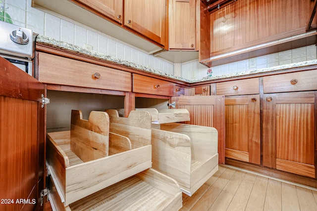 details featuring light stone counters, light hardwood / wood-style flooring, and decorative backsplash