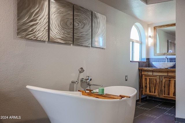 bathroom featuring a tub to relax in, vanity, and a textured ceiling