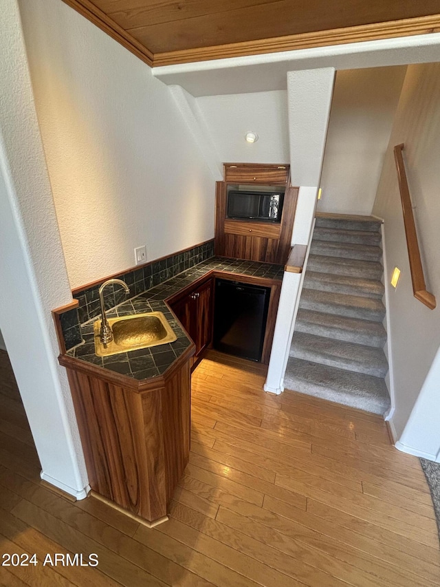 kitchen featuring sink, light hardwood / wood-style flooring, kitchen peninsula, and black appliances