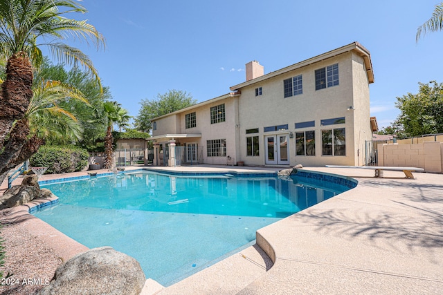 view of swimming pool with french doors, a patio area, and a diving board