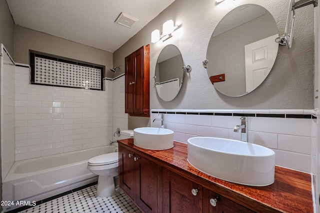 full bathroom featuring vanity, tiled shower / bath combo, tile patterned flooring, toilet, and a textured ceiling