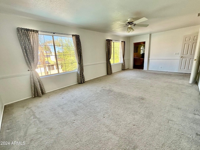 empty room featuring ceiling fan, a textured ceiling, and carpet