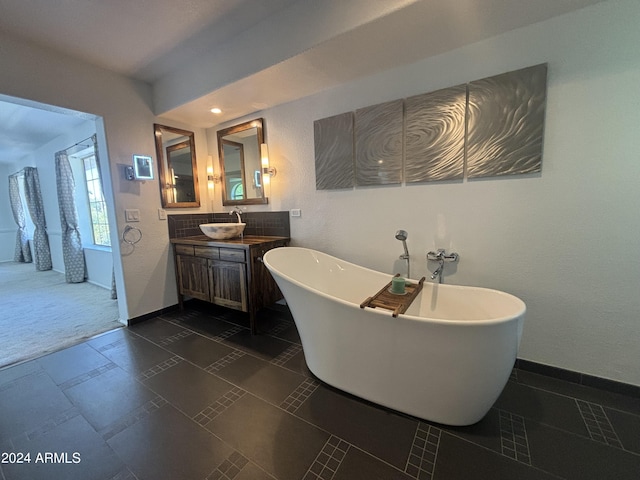 bathroom with vanity, a tub to relax in, and decorative backsplash