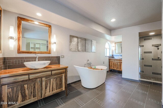 bathroom featuring decorative backsplash, vanity, plus walk in shower, and a textured ceiling