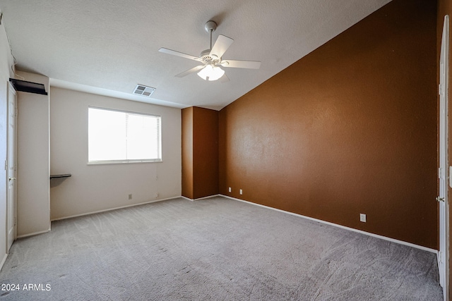 carpeted empty room with lofted ceiling, a textured ceiling, and ceiling fan