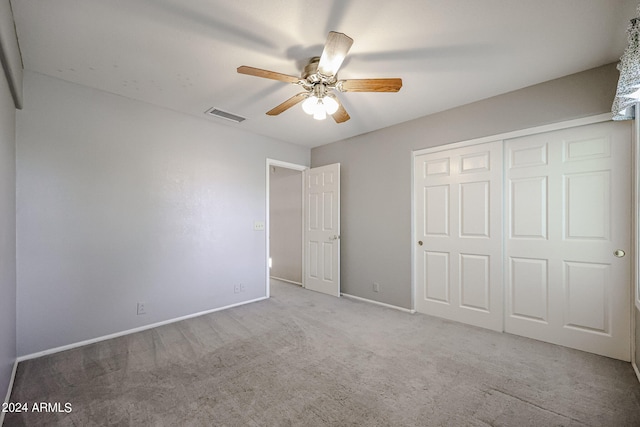 unfurnished bedroom featuring ceiling fan, light colored carpet, and a closet