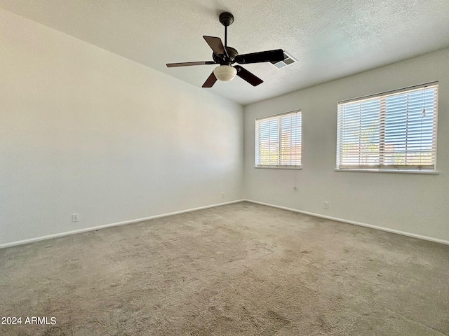 empty room featuring ceiling fan, a textured ceiling, and carpet