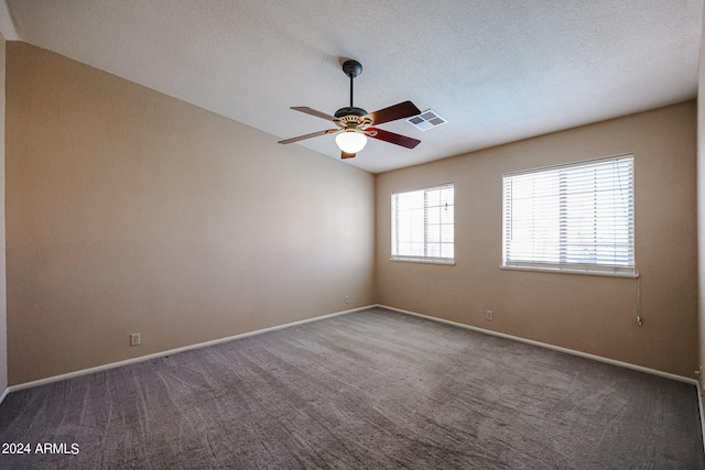 carpeted empty room featuring lofted ceiling, ceiling fan, and a textured ceiling