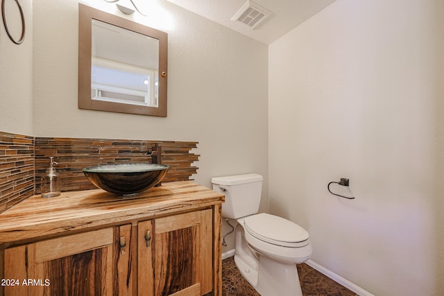 bathroom with vanity, toilet, and decorative backsplash