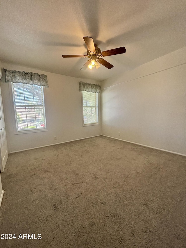 carpeted empty room with ceiling fan and a textured ceiling