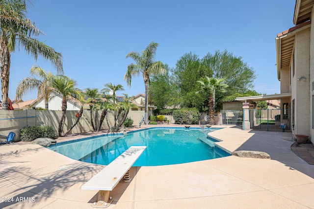 view of swimming pool featuring a diving board and a patio