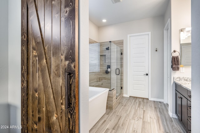 bathroom featuring hardwood / wood-style flooring, vanity, and separate shower and tub