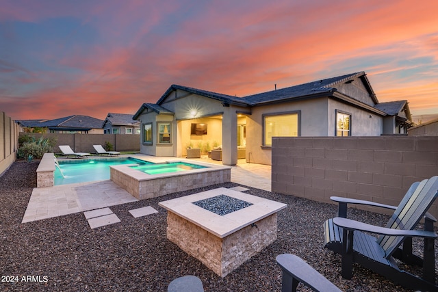 pool at dusk featuring pool water feature, a patio, an in ground hot tub, and a fire pit