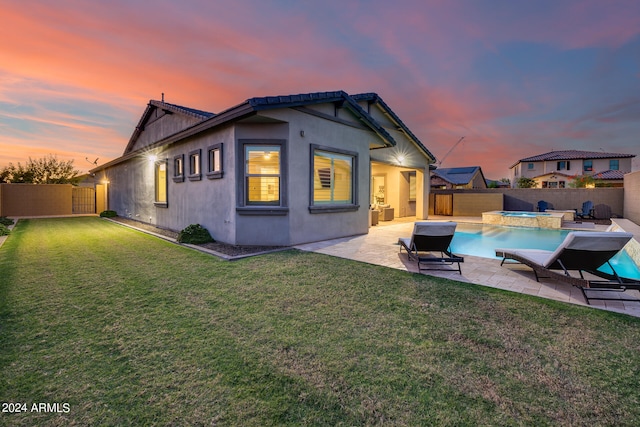 back house at dusk featuring a yard, a fenced in pool, and a patio area