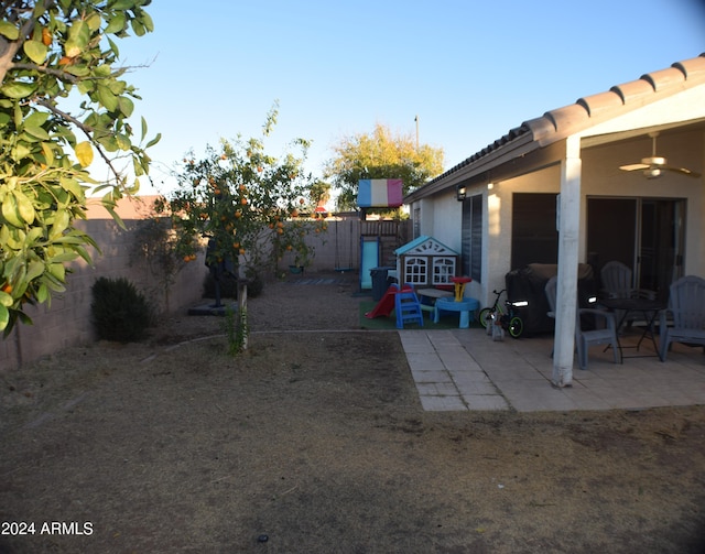 yard at dusk with a patio and ceiling fan