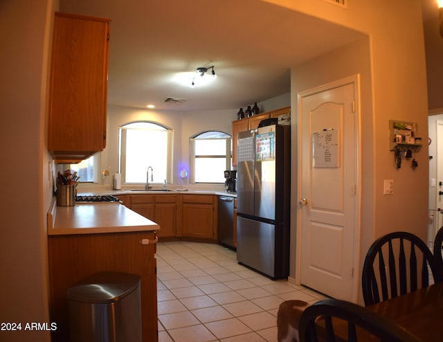 kitchen with light tile patterned flooring, appliances with stainless steel finishes, kitchen peninsula, and sink