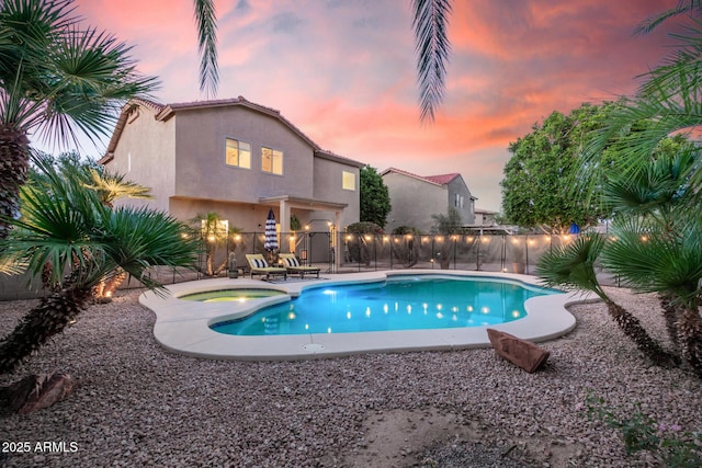 view of swimming pool with a fenced in pool, fence, and an in ground hot tub
