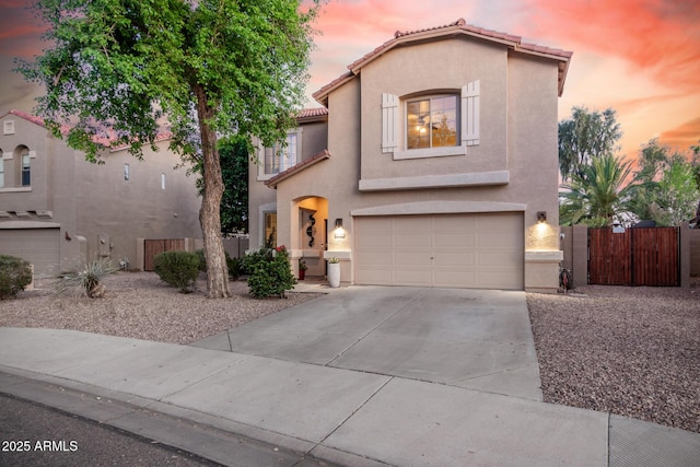mediterranean / spanish-style house featuring a garage, stucco siding, a gate, driveway, and a tile roof