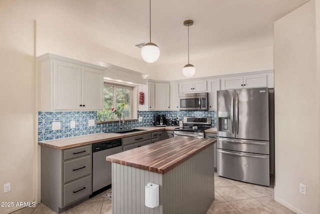 kitchen with decorative backsplash, wooden counters, white cabinetry, a sink, and stainless steel appliances