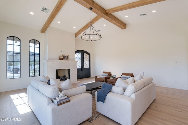 living room featuring a fireplace, light wood-type flooring, lofted ceiling with beams, and an inviting chandelier