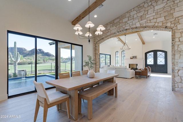 dining room featuring beamed ceiling, a mountain view, an inviting chandelier, and french doors