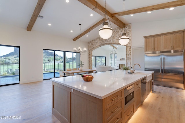 kitchen with pendant lighting, high vaulted ceiling, a large island with sink, built in appliances, and beam ceiling