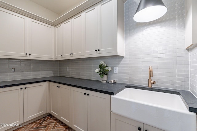 kitchen featuring white cabinets, backsplash, and sink