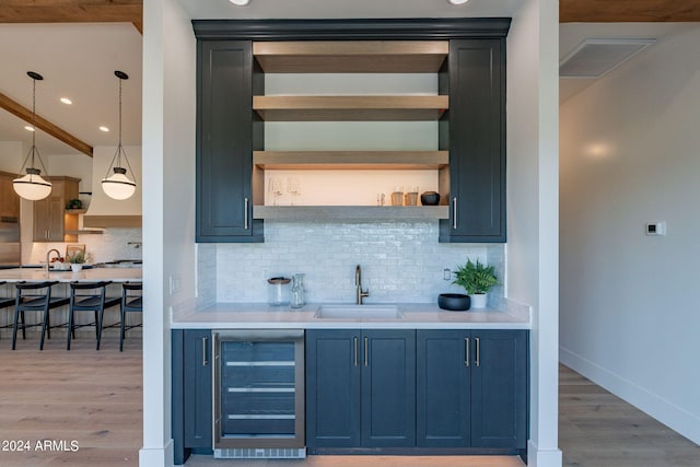 bar featuring sink, beverage cooler, tasteful backsplash, wood-type flooring, and decorative light fixtures