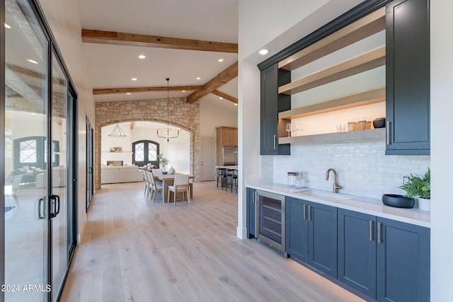 kitchen with sink, blue cabinetry, pendant lighting, vaulted ceiling with beams, and wine cooler