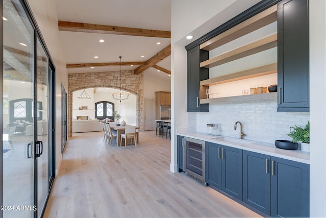 kitchen featuring sink, light hardwood / wood-style flooring, vaulted ceiling with beams, decorative light fixtures, and beverage cooler