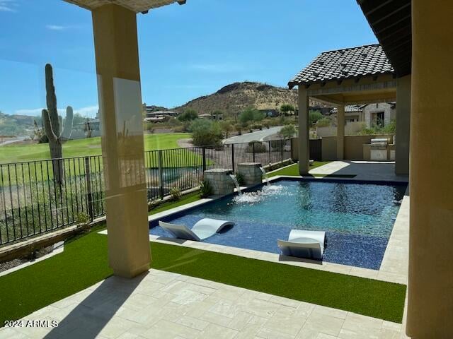 view of swimming pool with a mountain view, pool water feature, a patio, and exterior kitchen