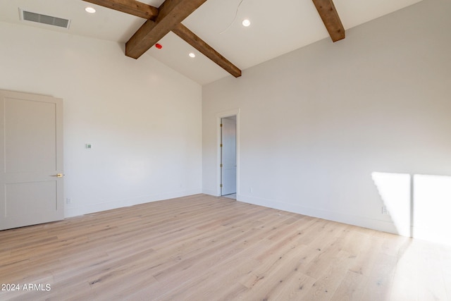 spare room featuring light hardwood / wood-style flooring and lofted ceiling with beams