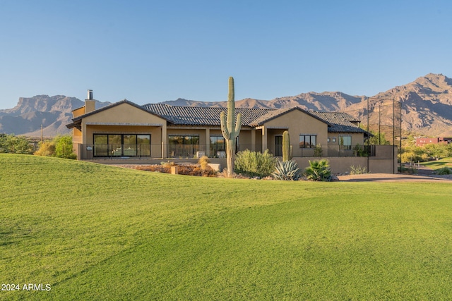 back of house with a mountain view and a yard