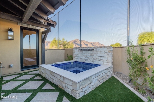 view of patio / terrace featuring an in ground hot tub and a mountain view