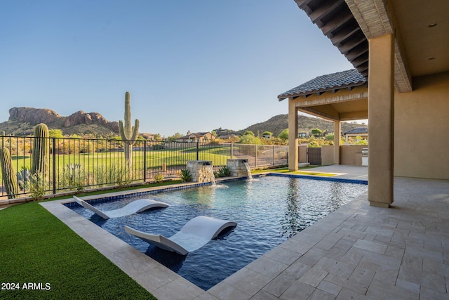 view of swimming pool with a mountain view, pool water feature, and a patio area