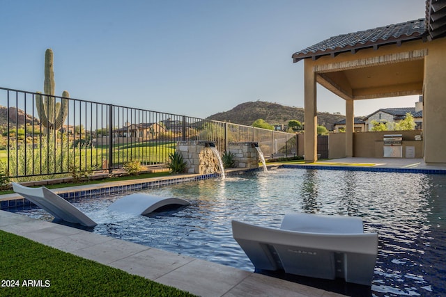 view of swimming pool with area for grilling, pool water feature, and a mountain view