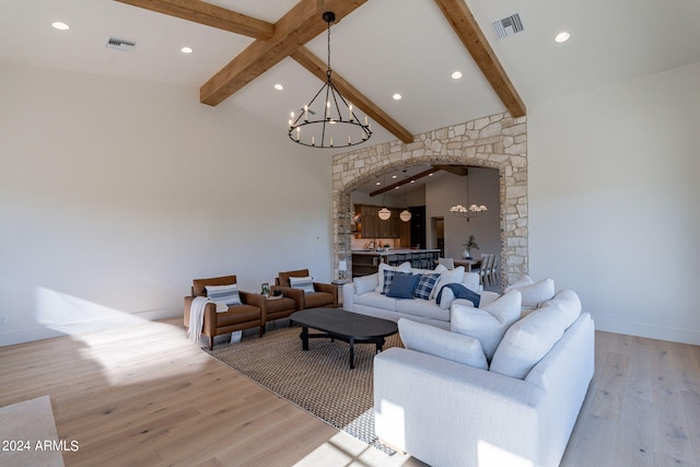 living room with a chandelier, vaulted ceiling with beams, and light hardwood / wood-style flooring